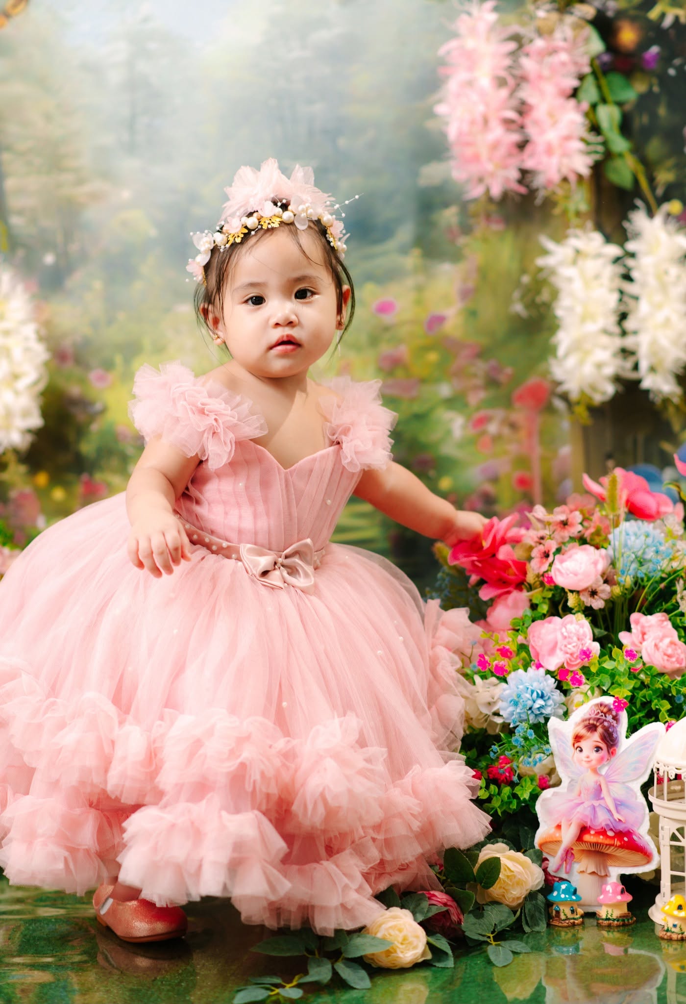 Amara Izabella in a pink dress and floral crown, surrounded by flowers in a fairy garden